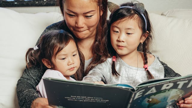 Woman and children reading a book together